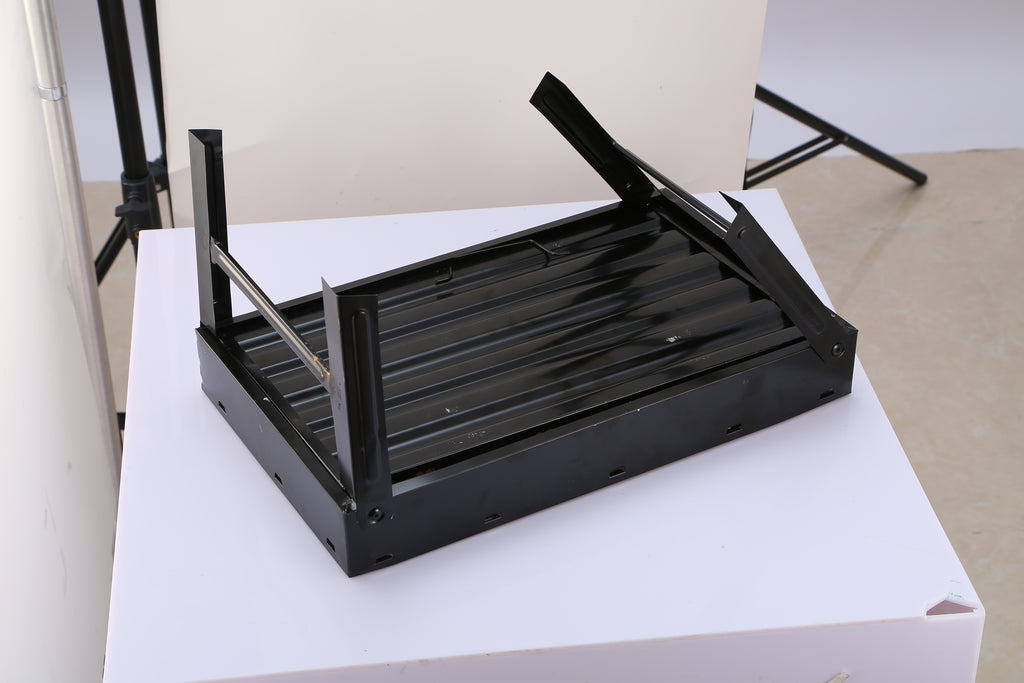 Folded black charcoal grill frame with wire grate on tabletop