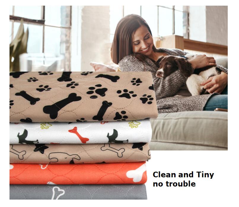 Orange reusable pet absorbent pad with paw-print and bone pattern, folded