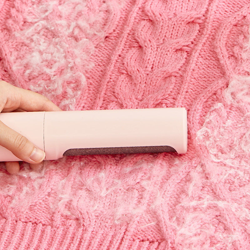 Pink self-cleaning lint roller brush removing hair from pink knit sweater