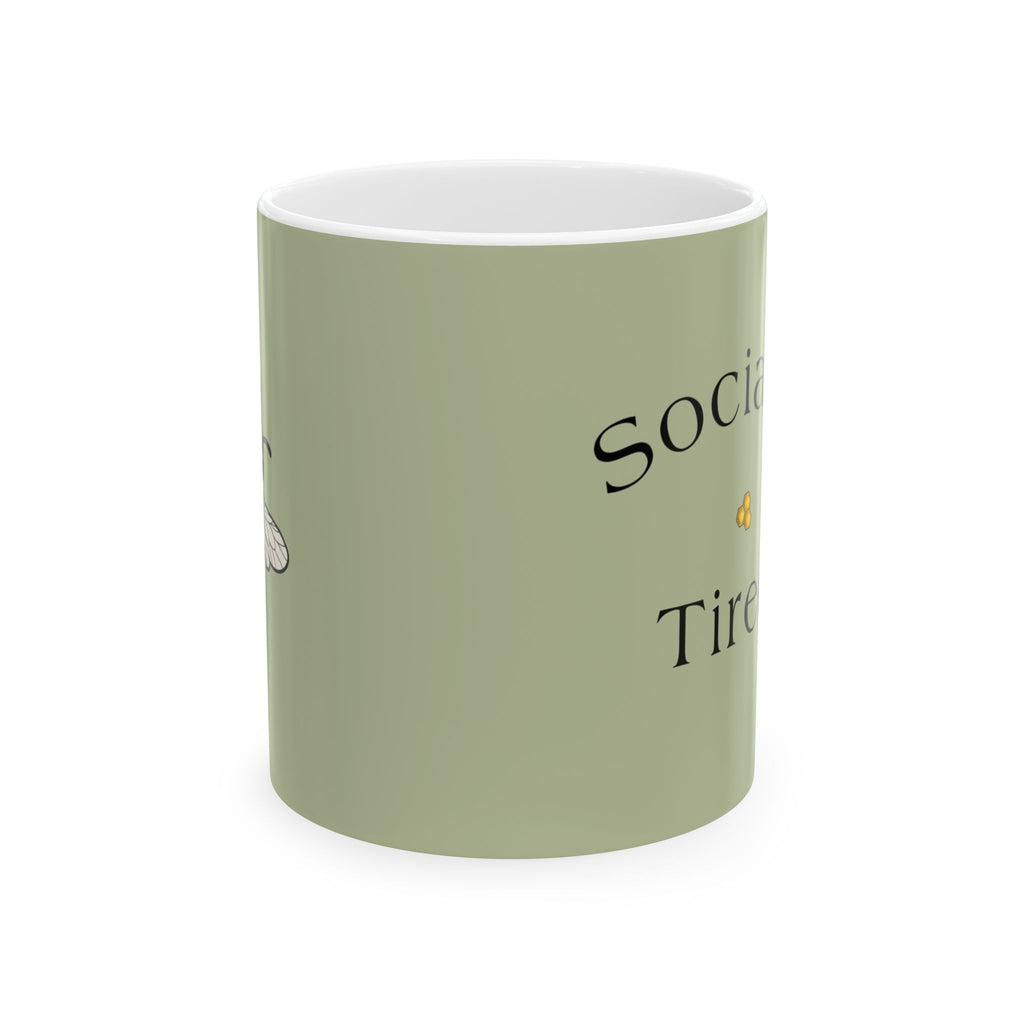 Light green ceramic mug with black 'Social...' and 'Tired' text, white rim.
