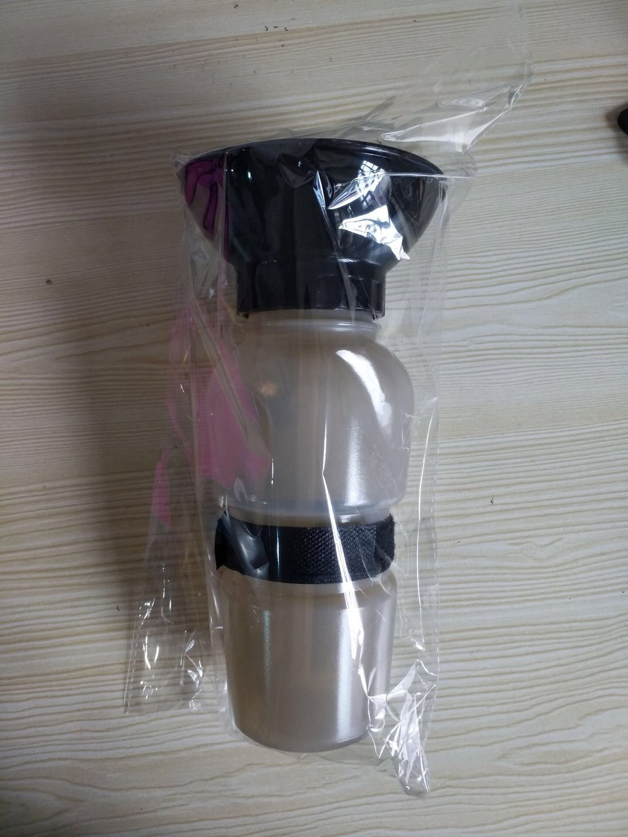 Packaged portable pet water bottle with black bowl and white bottle; carry strap included.