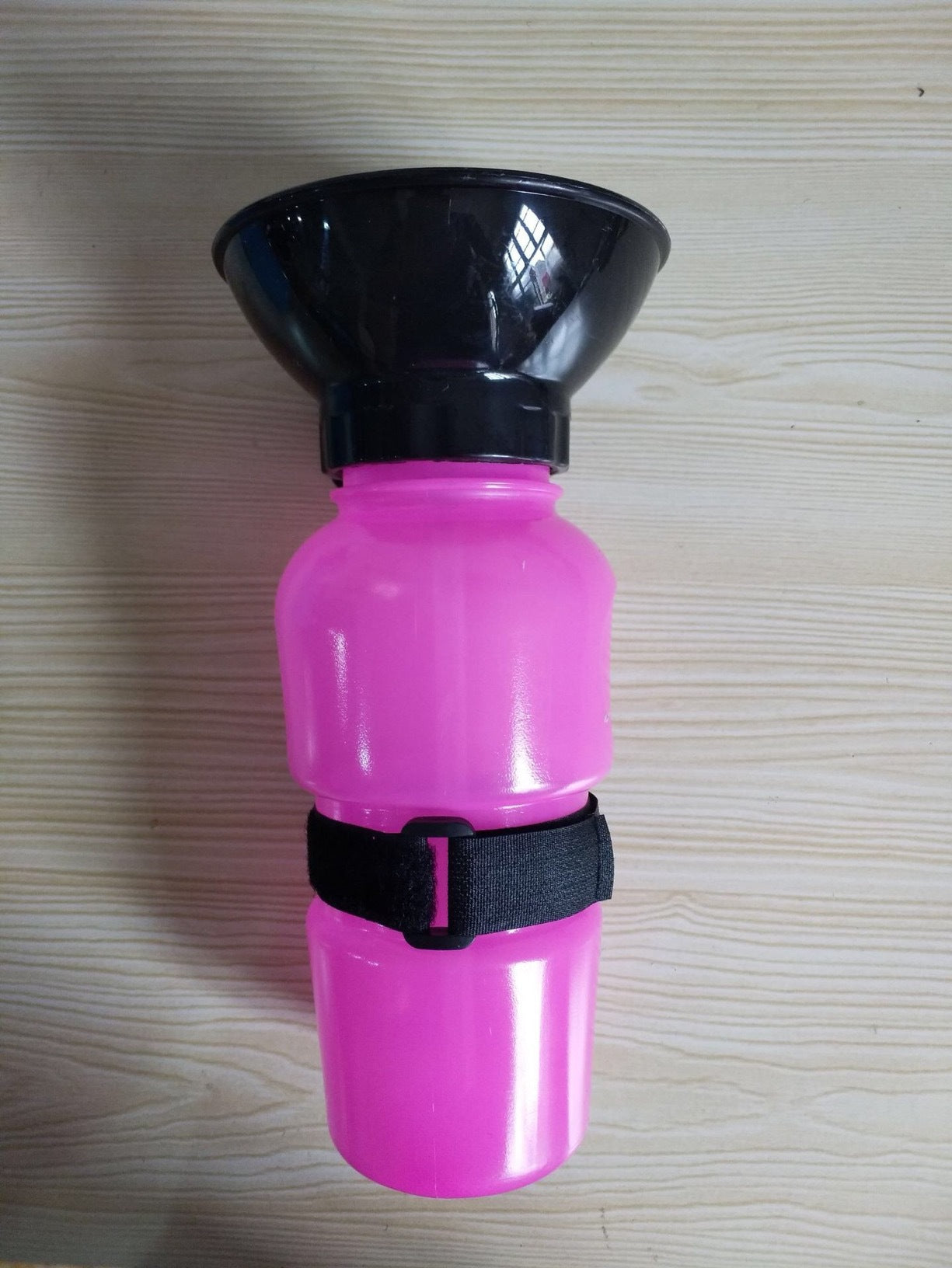 Hot pink portable pet water bottle with attached black bowl and black carry strap.