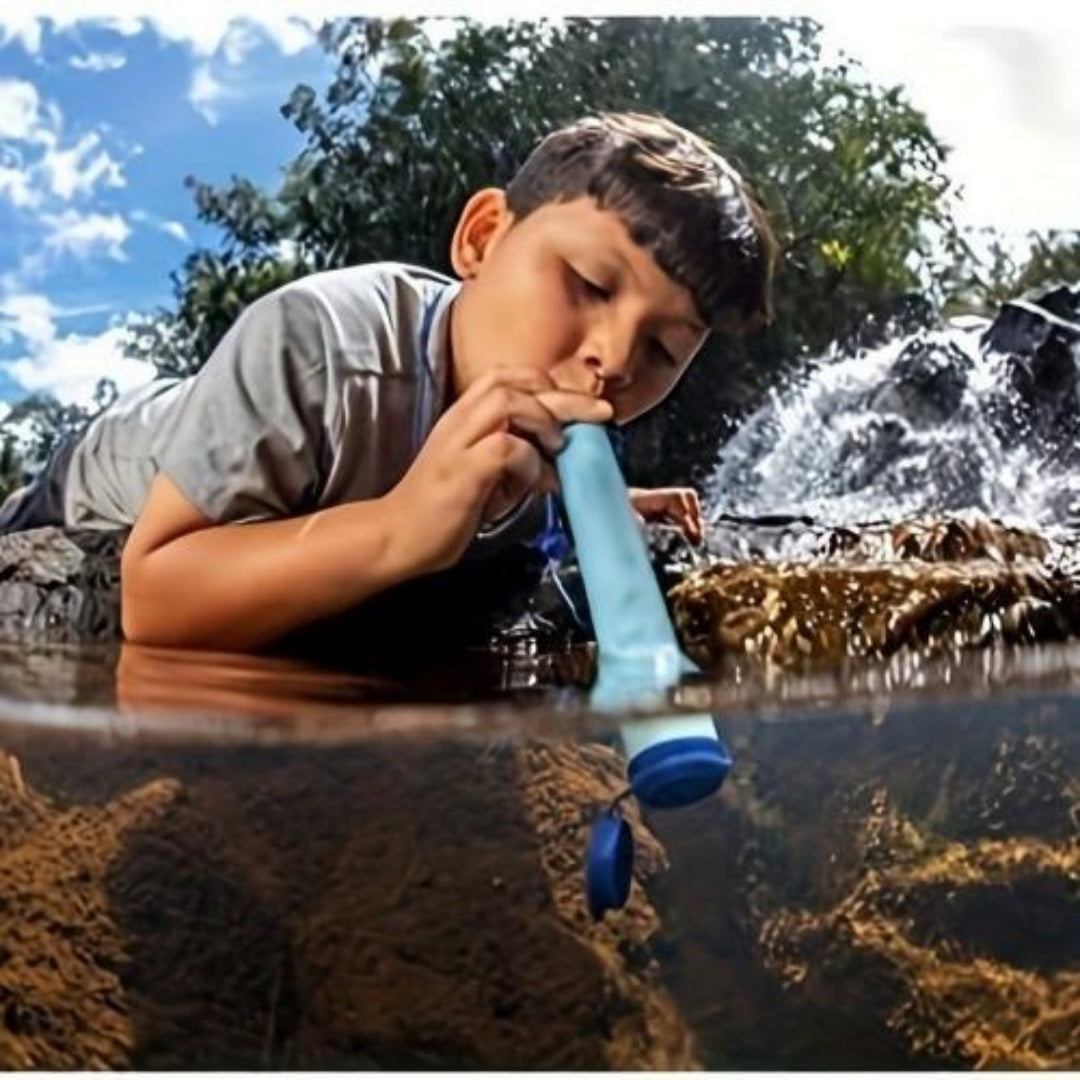 Blue portable water filter with hose held while drinking outdoors