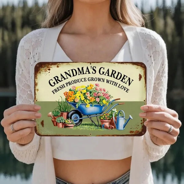 Vintage metal garden sign held up, GRANDMA'S GARDEN headline with wheelbarrow and watering can