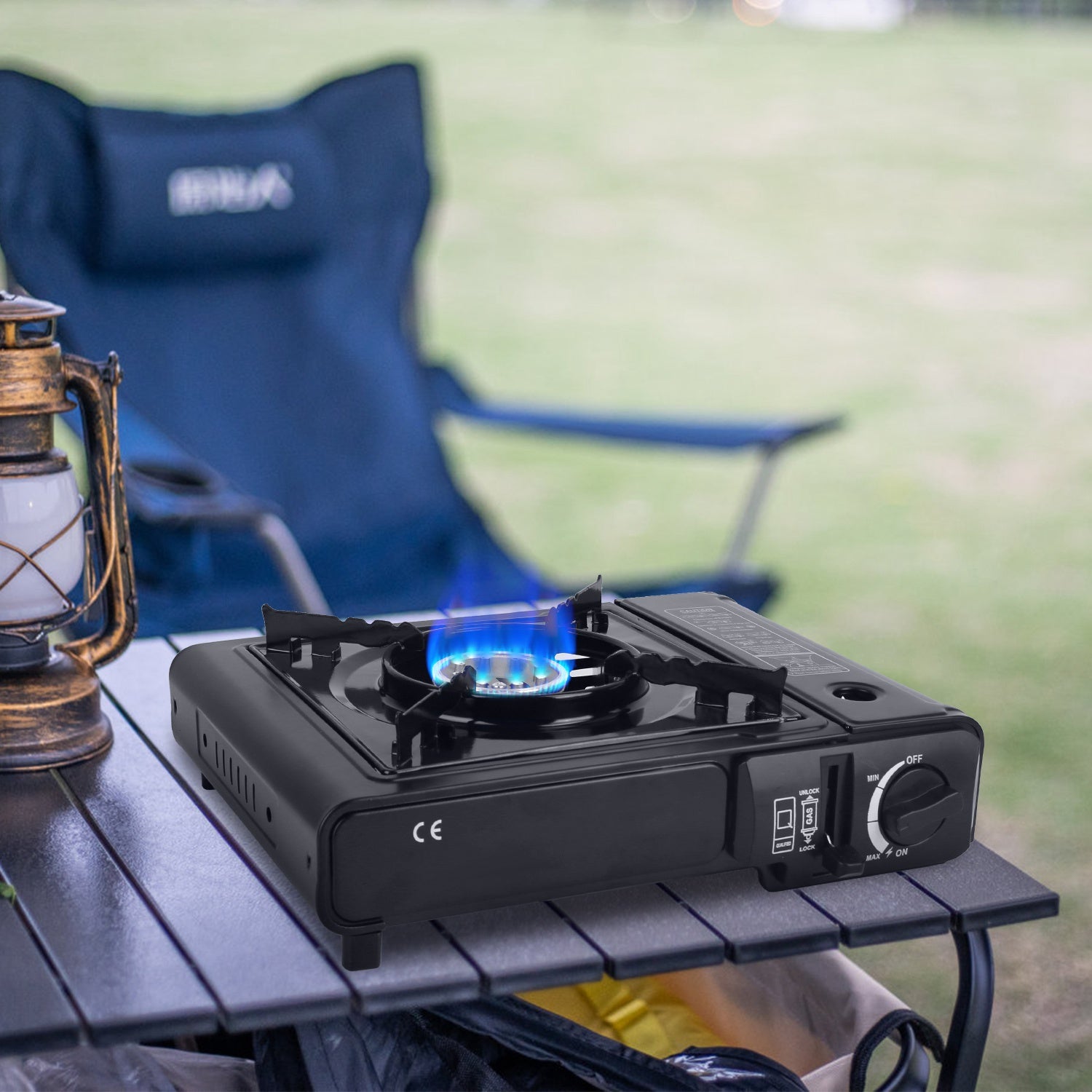 Black camp stove with blue flame on tabletop, control dial visible