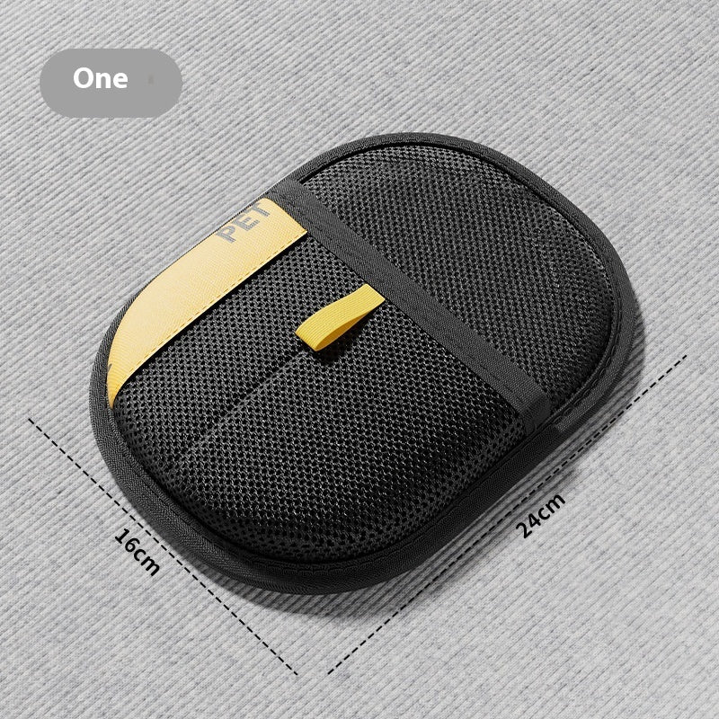 Black pet hair removal brush pad with yellow center accents and textured oval surface