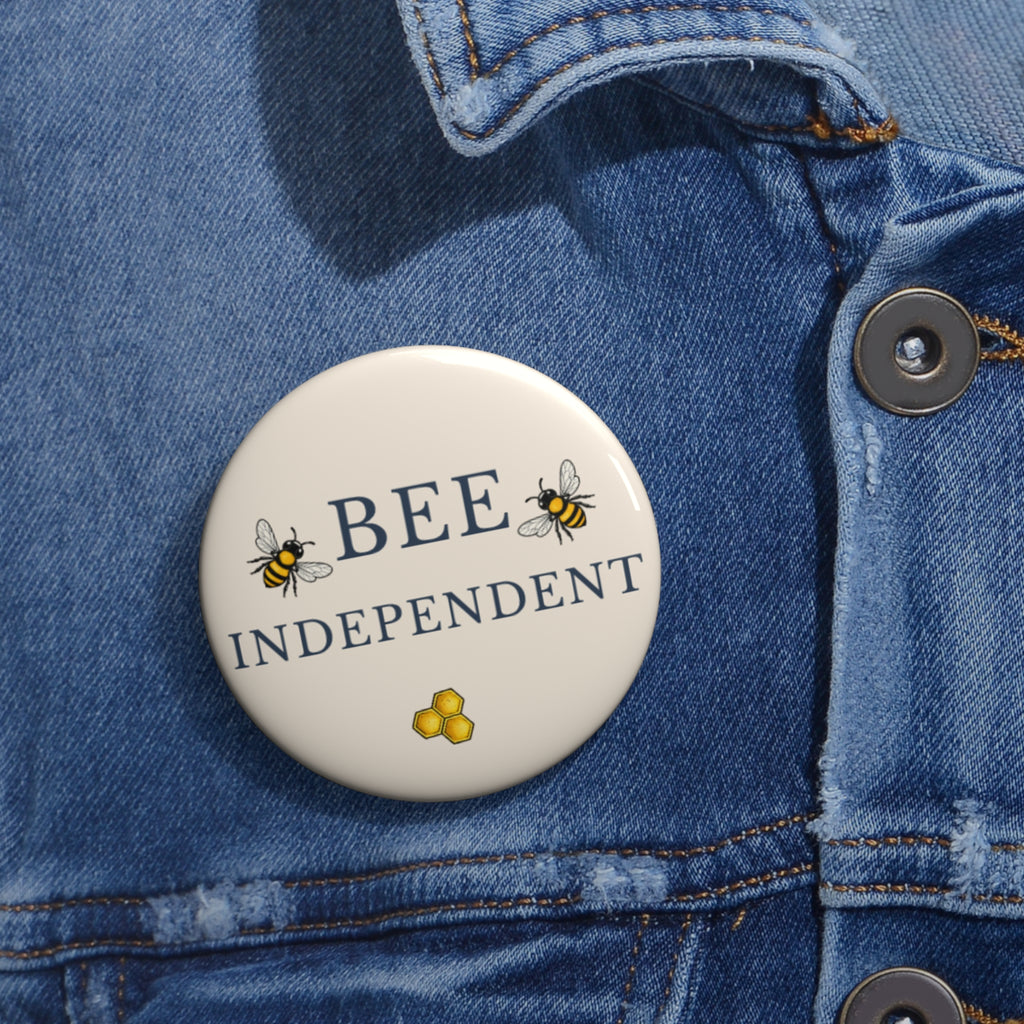 Bee pin badge on blue denim jacket, cream circle with BEE INDEPENDENT text and honeycomb