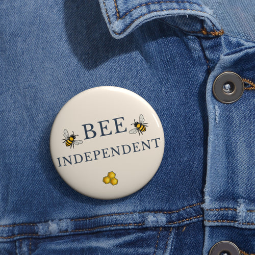 Bee pin badge on blue denim jacket, cream circle with BEE INDEPENDENT text and honeycomb