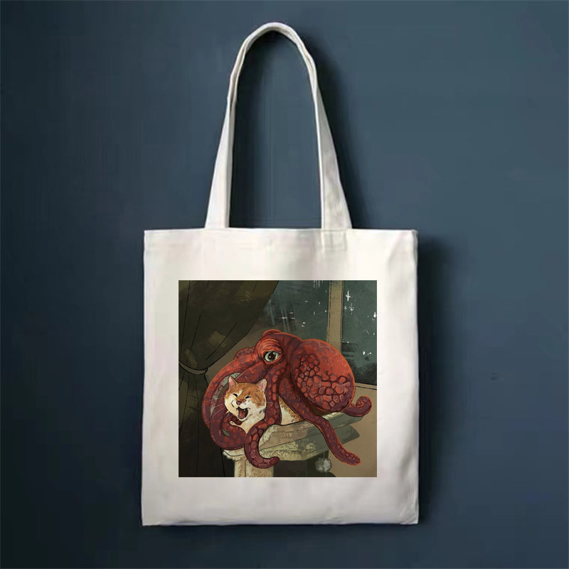 Canvas tote bag, white, with red creature and small cat print.