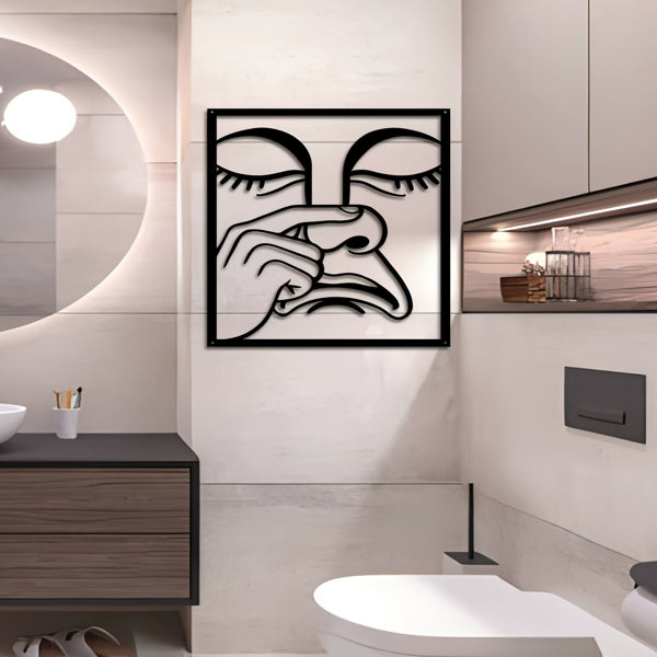 Square metal wall art on a bathroom wall with black line nose-picking face
