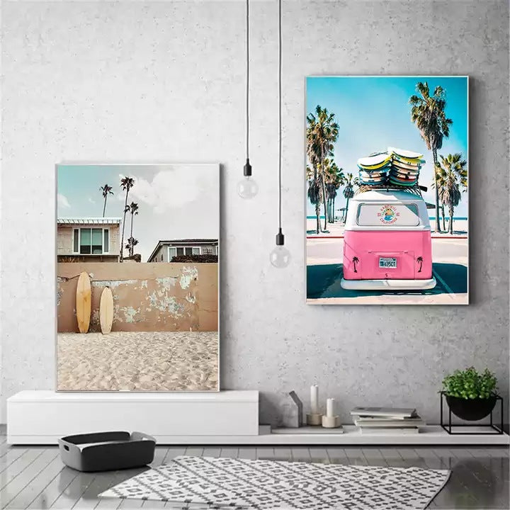Two framed beach canvas prints on a concrete wall above a black table and rug