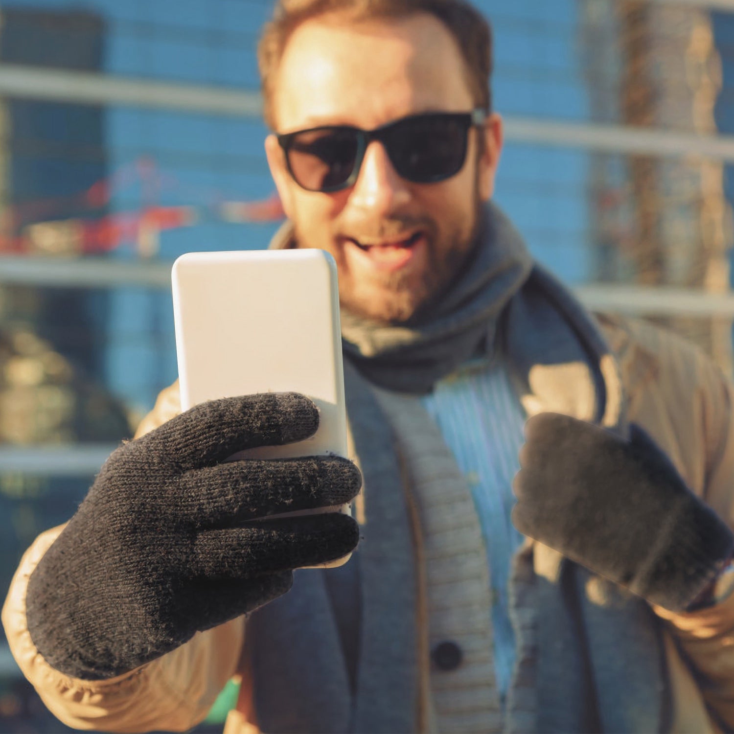 Man holding a tablet while wearing dark knit touchscreen gloves with three-finger tips.
