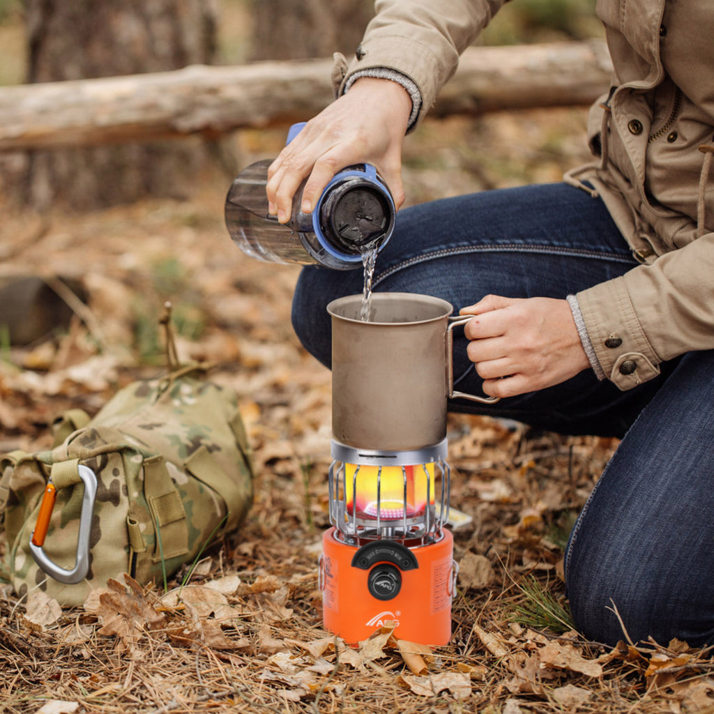 Orange outdoor gas stove and heater heating a pot outdoors while camping