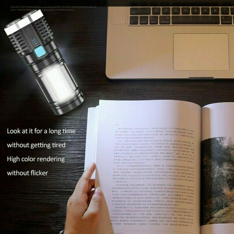 Black tactical flashlight shining on an open book near a laptop