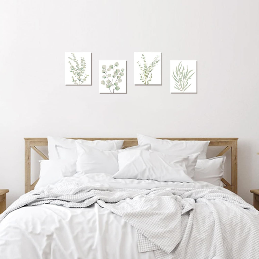 Four framed botanical leaf canvas prints displayed above a bed