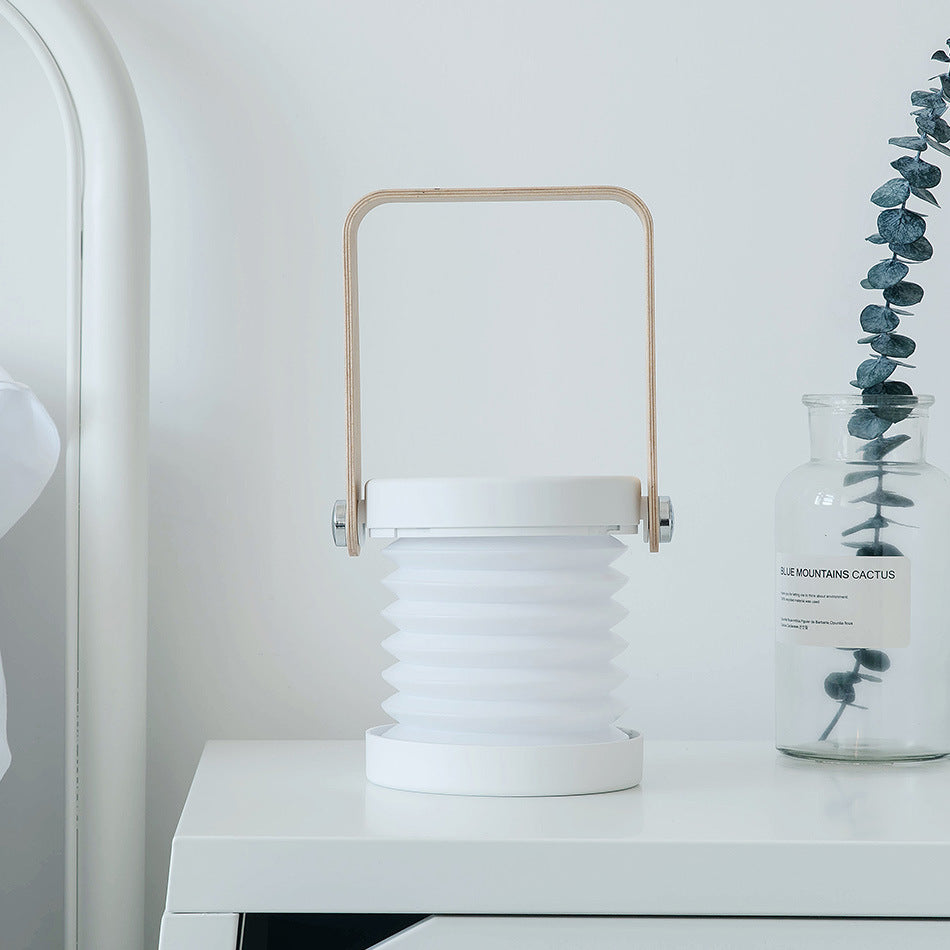 Foldable LED night lantern with white ridged body and wood carry handle, unlit