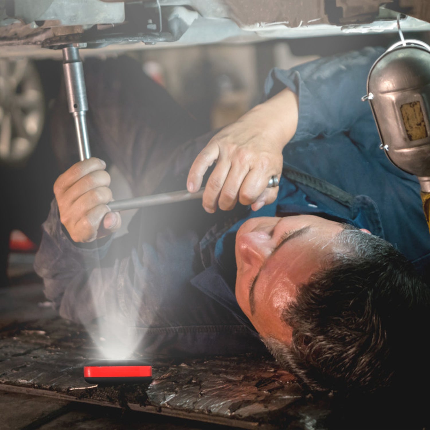 Portable LED work light projecting a beam in a workshop setting, red indicator light