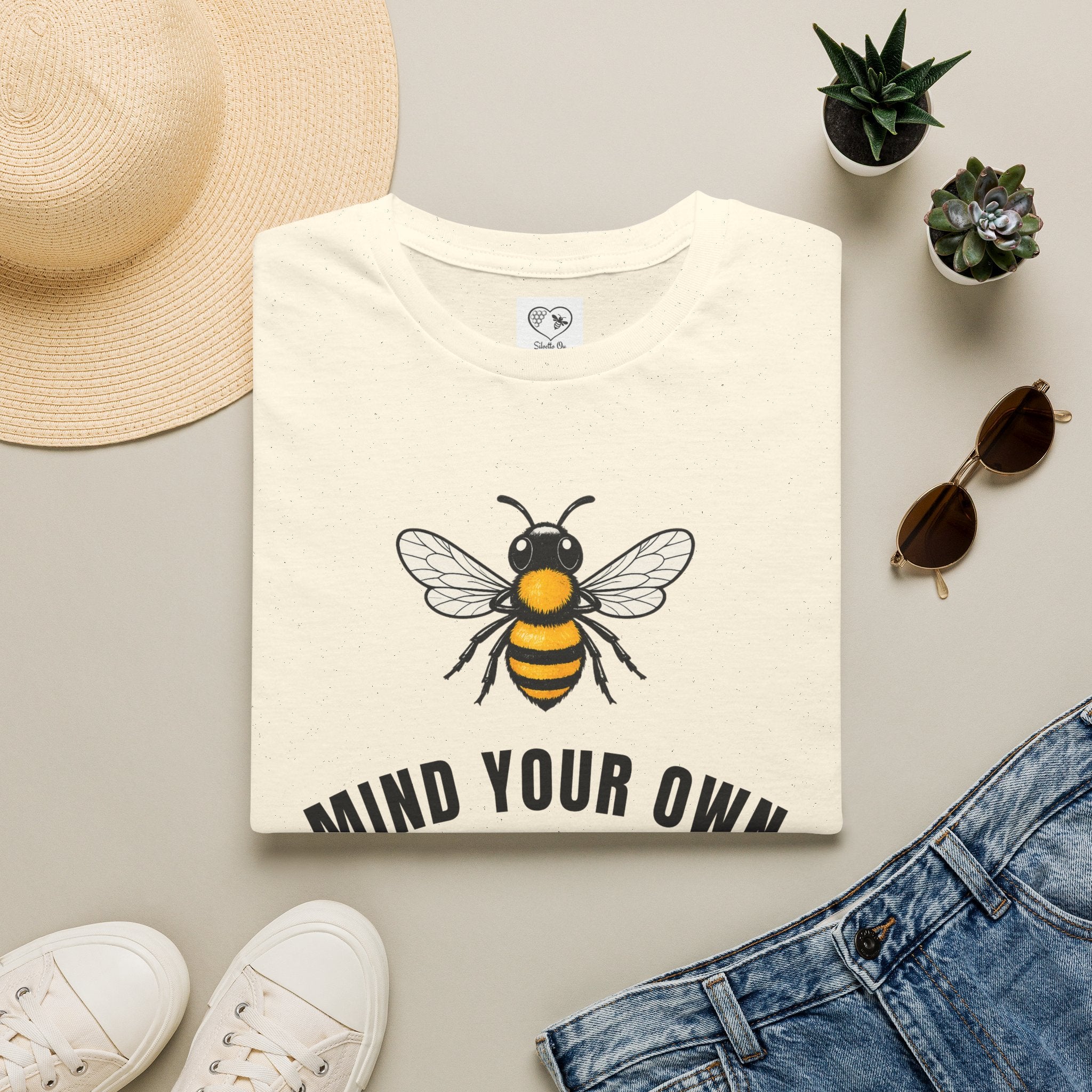 Light cream t-shirt with bee illustration and bold "MIND YOUR OWN" text on front