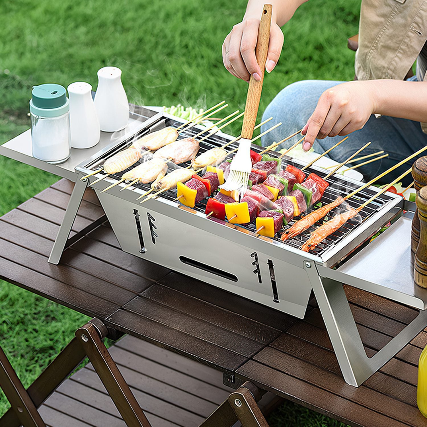 Foldable stainless steel grill with cooking grate, food on skewers and vegetables grilling
