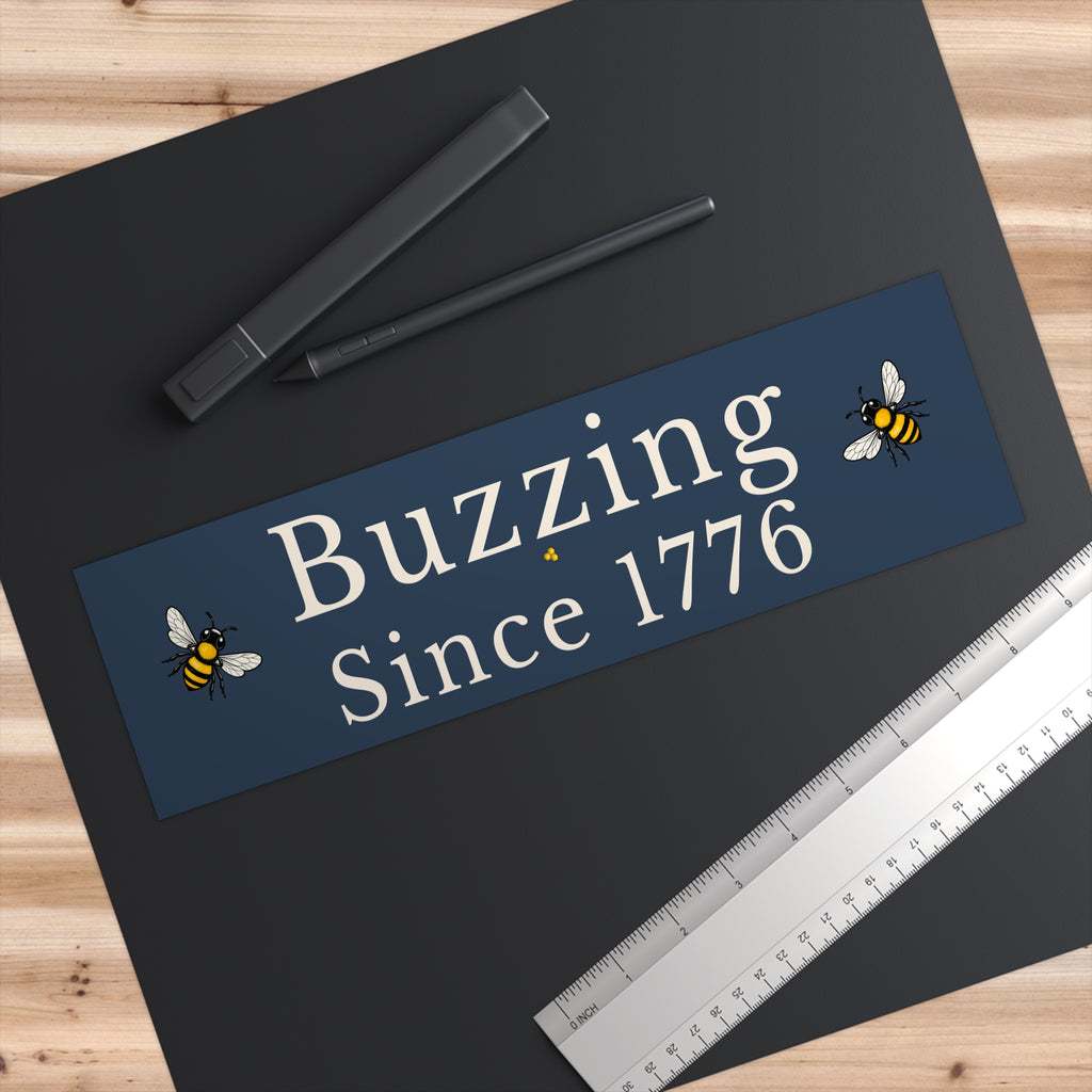 Rectangle bumper sticker on a dark surface with 'Buzzing Since 1776' and bee icons