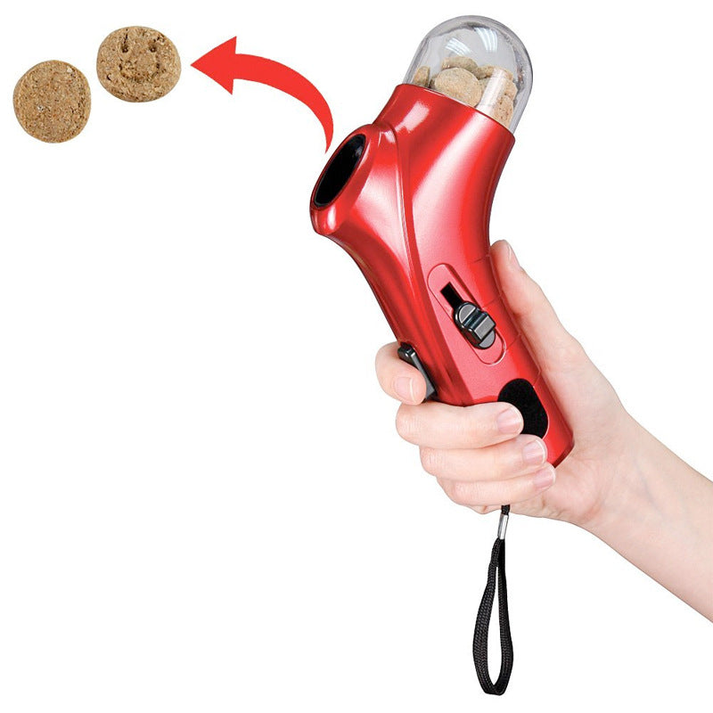 Red handheld pet snack feeder with clear treat chamber and wrist strap, held in hand.
