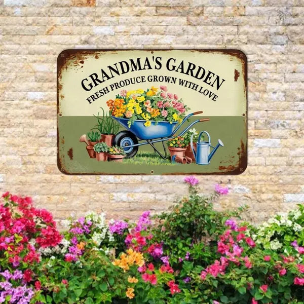 Vintage metal garden sign mounted on brick, GRANDMA'S GARDEN text over colorful garden scene