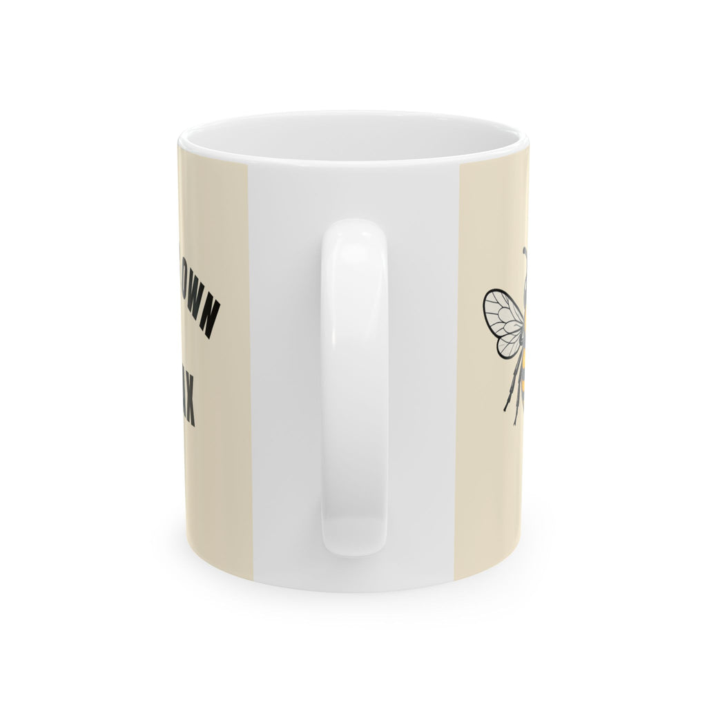 Light cream ceramic mug with white interior, partial black text and bee line art