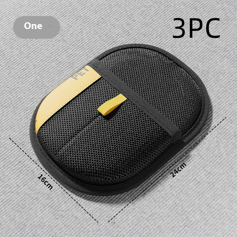 Black pet hair removal brush pad with yellow accents and textured oval cleaning surface