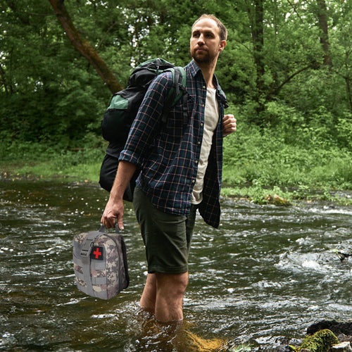 Tactical first aid bag with red medical cross, carried by a hiker in shorts