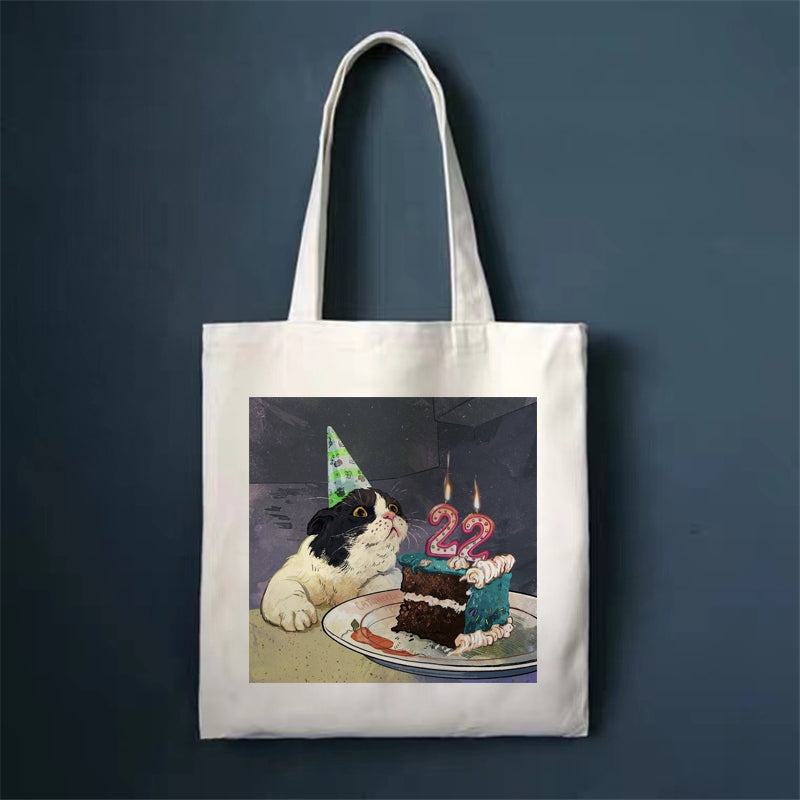 Canvas tote bag with cat eating cake illustration, square front print and long handles