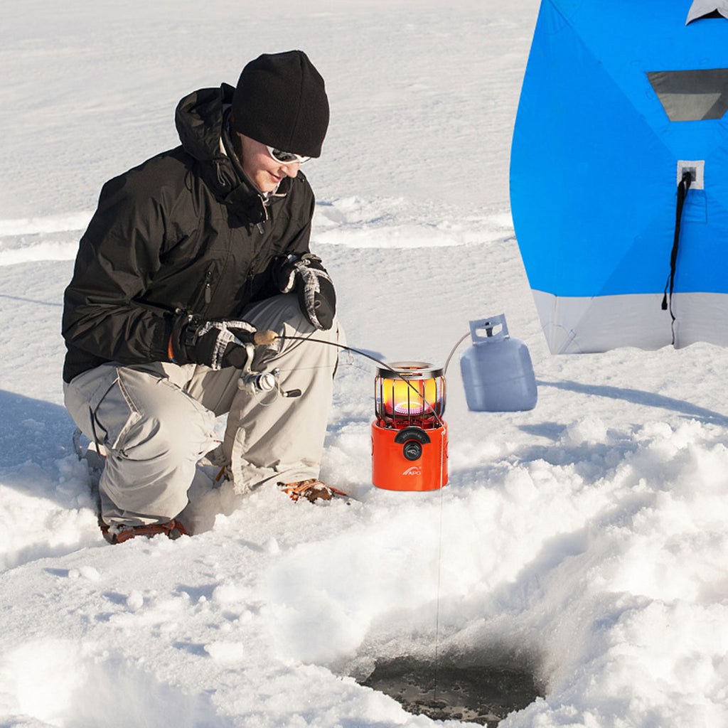 Orange outdoor gas stove and heater on snow with protective metal guard