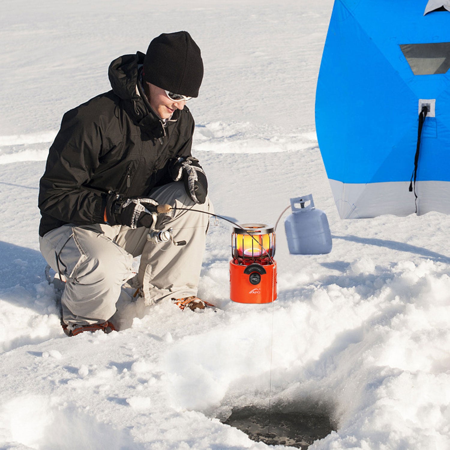 Orange outdoor gas stove and heater on snow with protective metal guard
