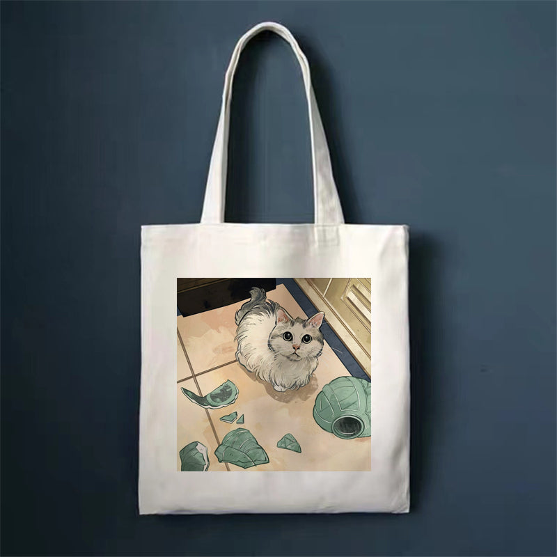 Canvas tote bag with cat illustration surrounded by green items on front panel.