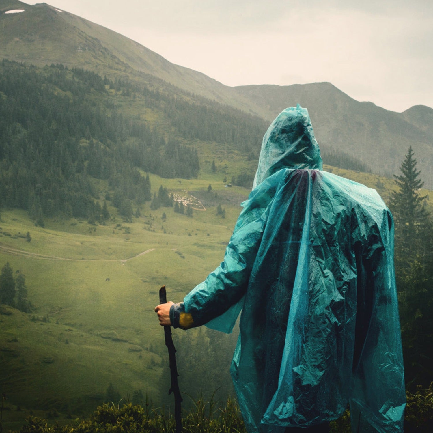 Emergency rain poncho tarp with hood carried over a person outdoors