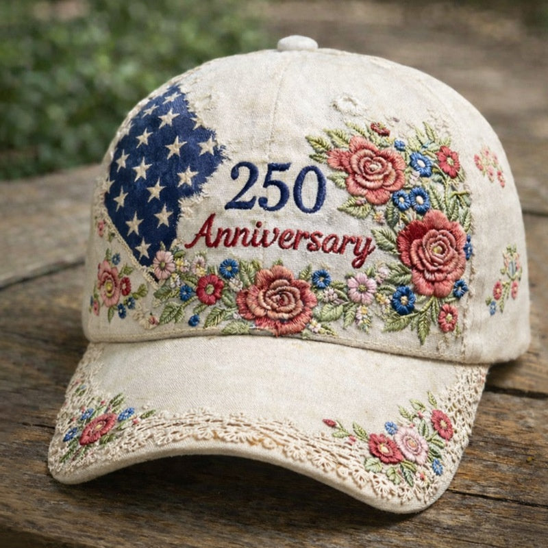 Beige baseball cap with “250 Anniversary” text and rose floral embroidery across the front