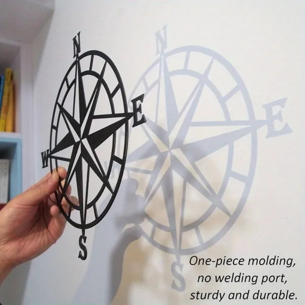 Compass rose metal wall art being positioned by hand, black ring with N, E, S, W labels