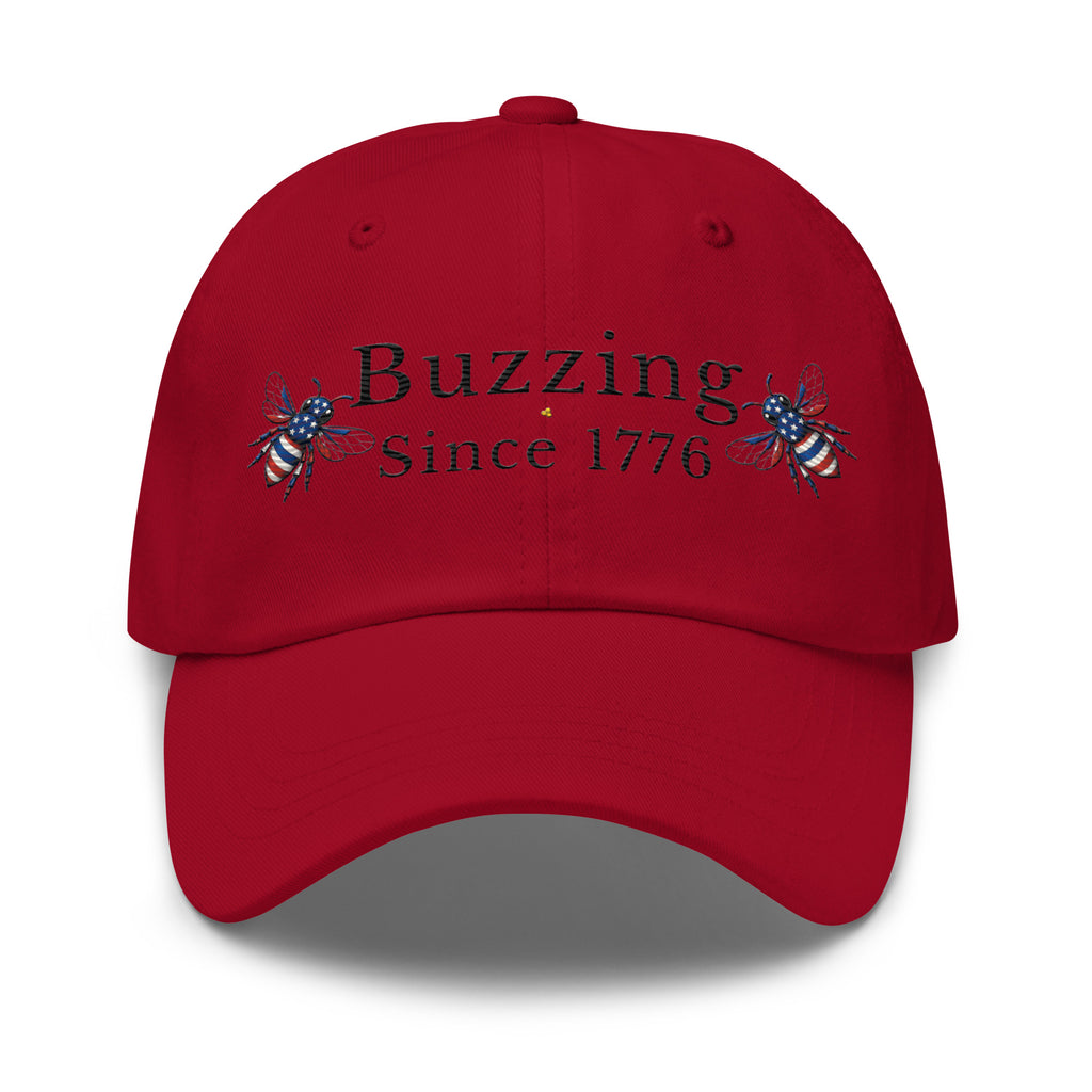 Cranberry red dad hat with 'Buzzing Since 1776' lettering and bee graphic
