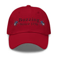 Cranberry red dad hat with 'Buzzing Since 1776' lettering and bee graphic