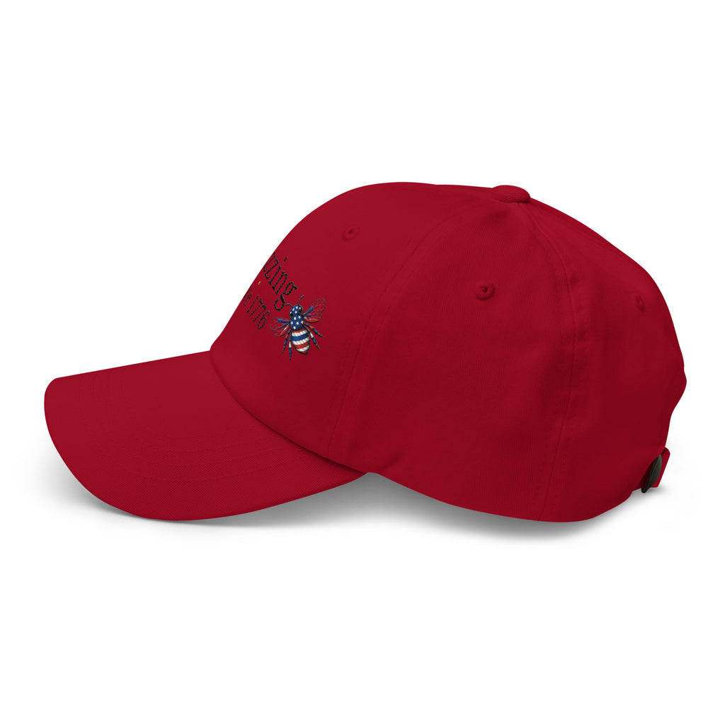 Red dad hat with curved brim and embroidered bee graphic on side