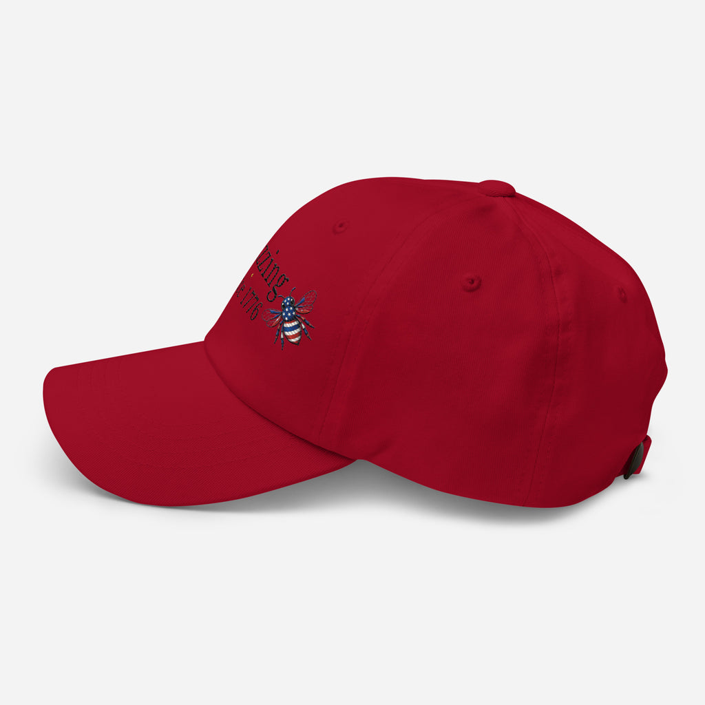 Red dad hat with embroidered bee logo on side, curved brim