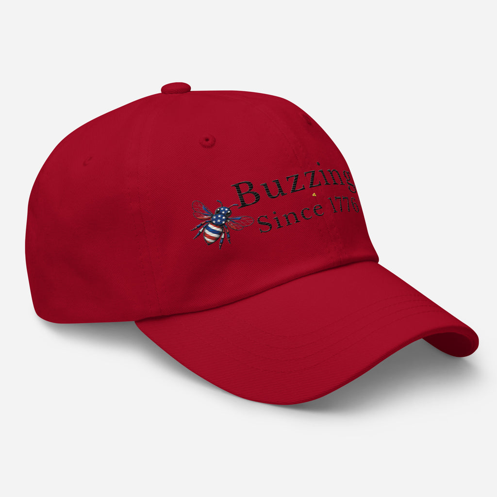 Cranberry red dad hat with embroidered bee and “Buzzing Since 1776” text on front