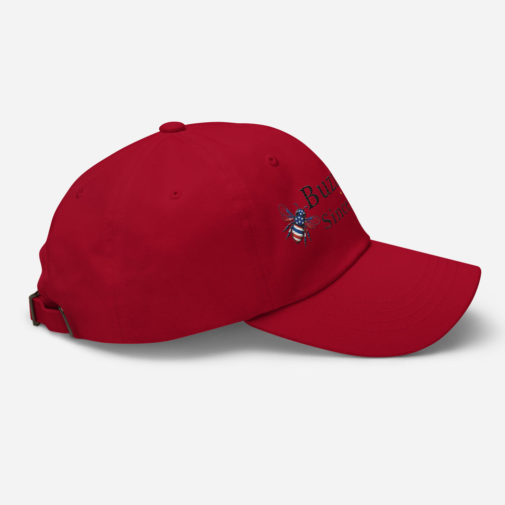 Cranberry red dad hat with adjustable strap and embroidered emblem on side