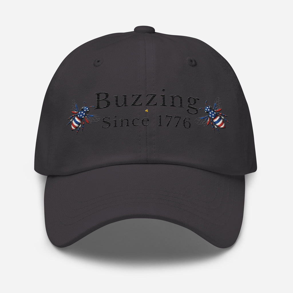 Dark grey dad hat with “Buzzing Since 1776” text and bee graphic embroidery on front