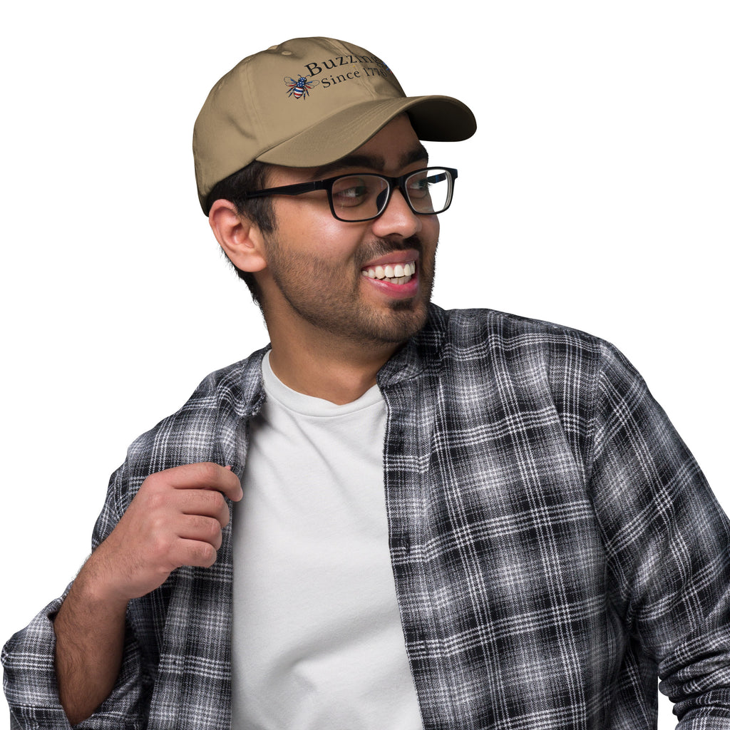 Khaki dad hat with curved brim and embroidered bee with “Buzzing Since 1776”