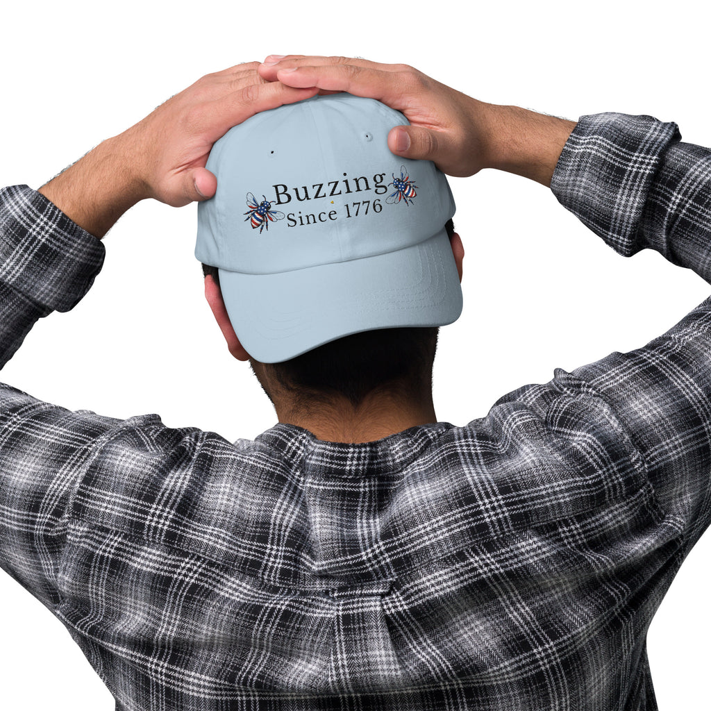 Light blue dad hat with embroidered “Buzzing Since 1776” on back