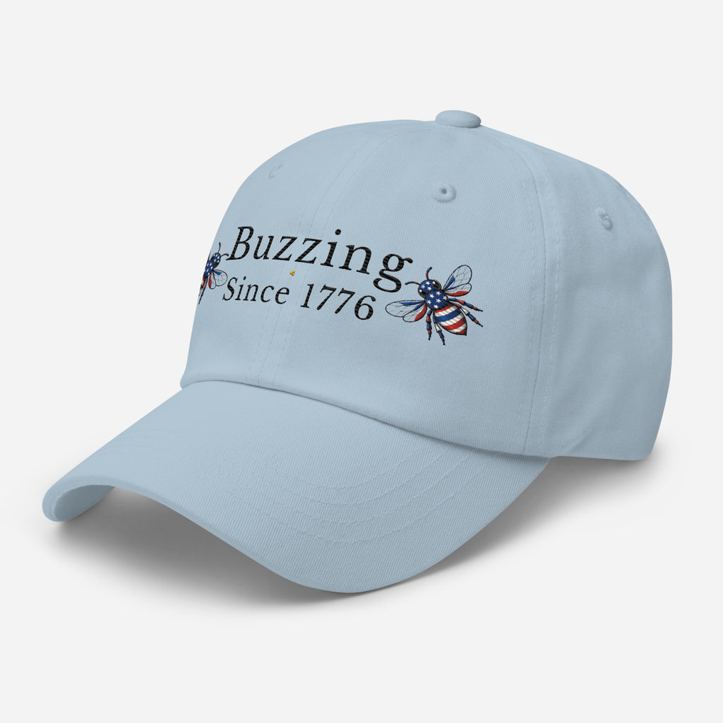 Light blue dad hat with embroidered bee and Buzzing Since 1776 text