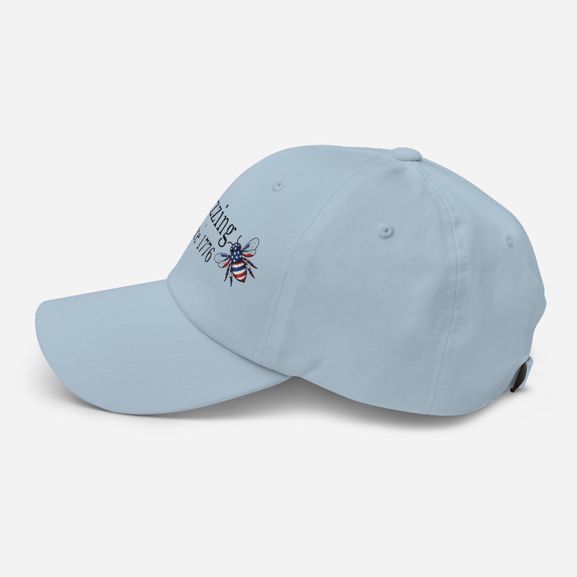 Light blue dad hat with embroidered bee and “Buzzing Since 1776” text on front