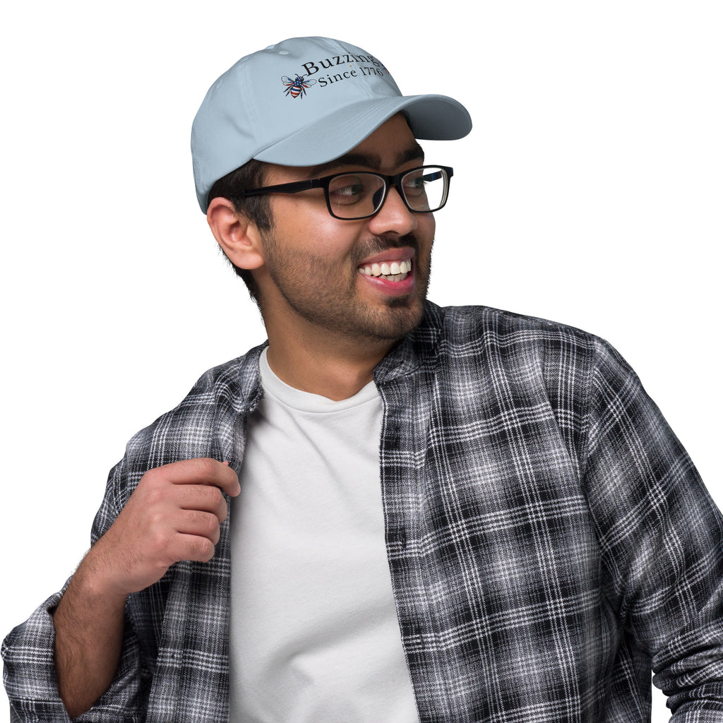 Light blue dad hat with embroidered “Buzzing Since 1776” on front