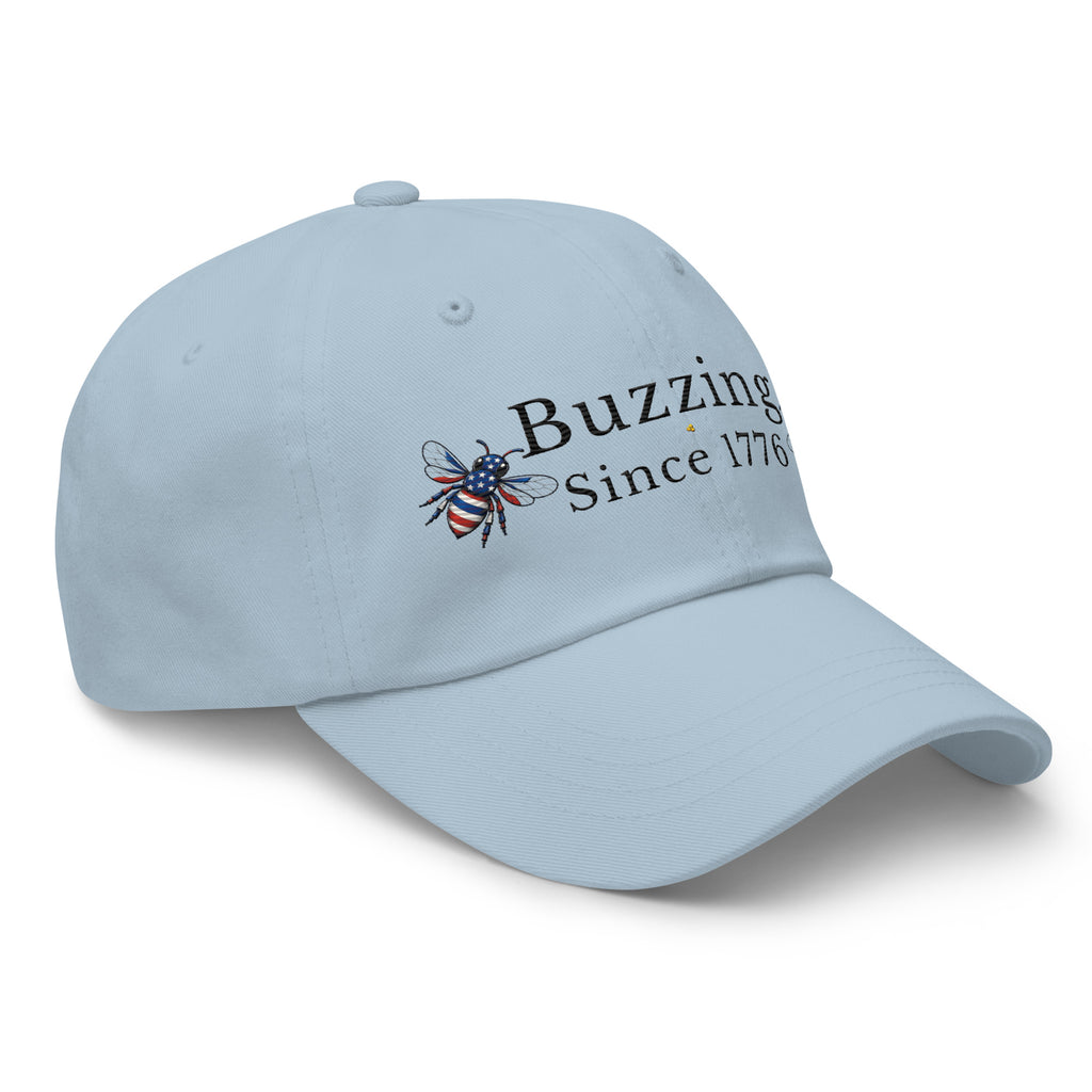 Sky blue dad hat with “Buzzing Since 1776” and bee logo embroidery