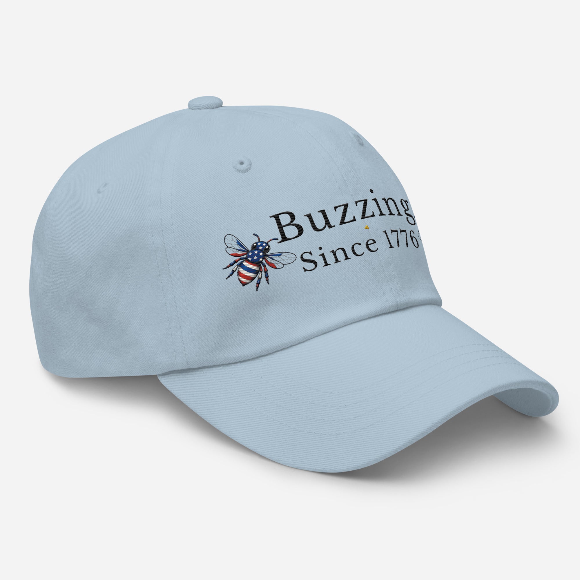 Light blue dad hat with embroidered bee and “Buzzing Since 1776” text on front